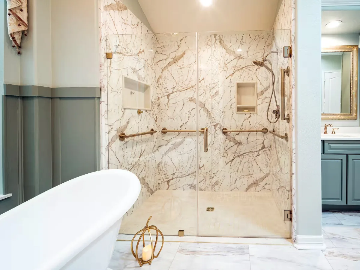 Marble-look walk-in shower with champagne bronze fixtures, built-in niches, and glass doors