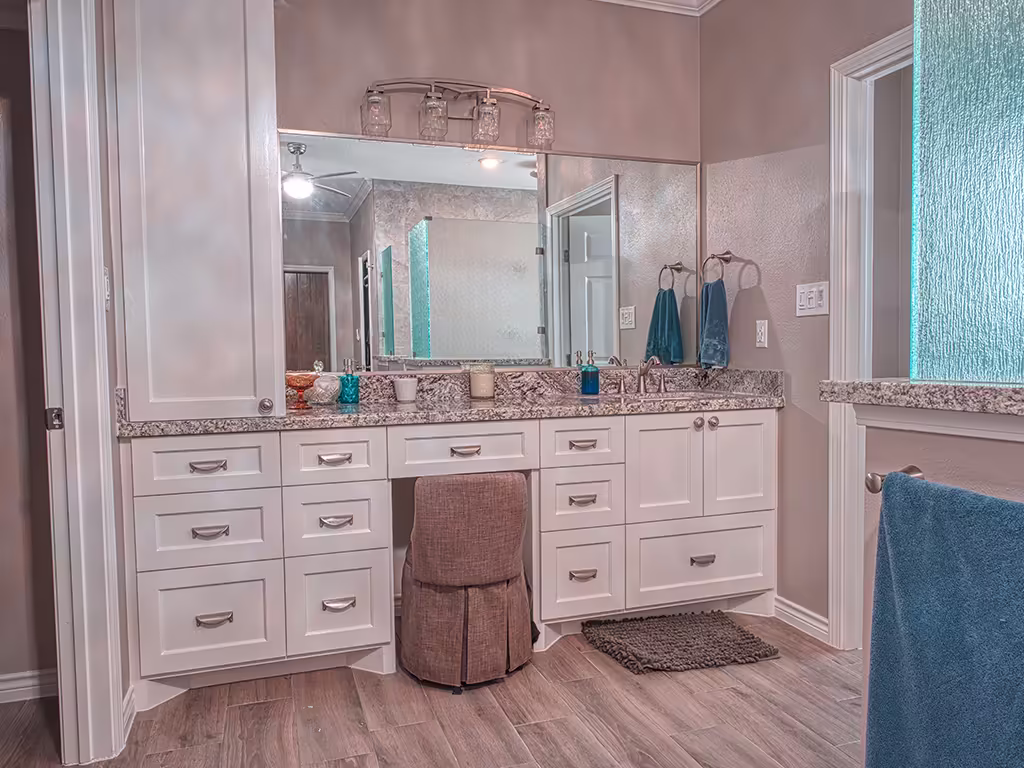 Custom white bathroom cabinets with granite countertop and vanity seating area
