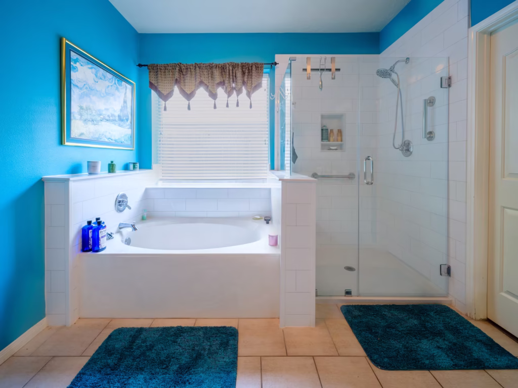 Soaking tub with glass shower enclosure and bold blue accent wall