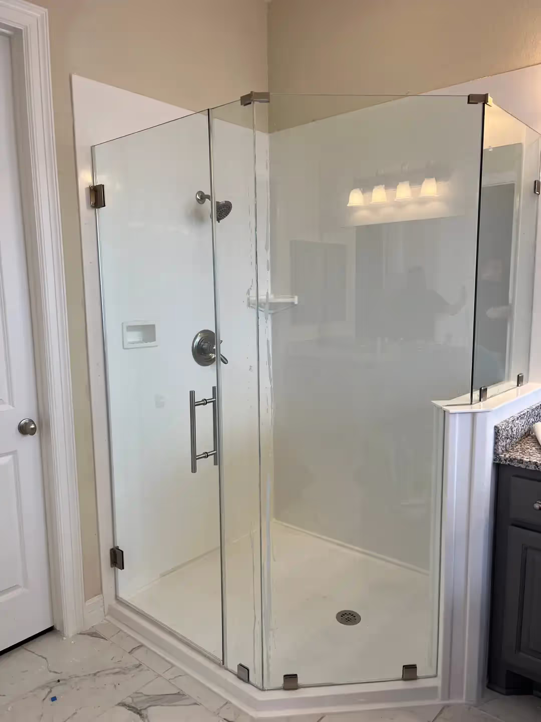 Frameless glass shower enclosure with chrome hardware.