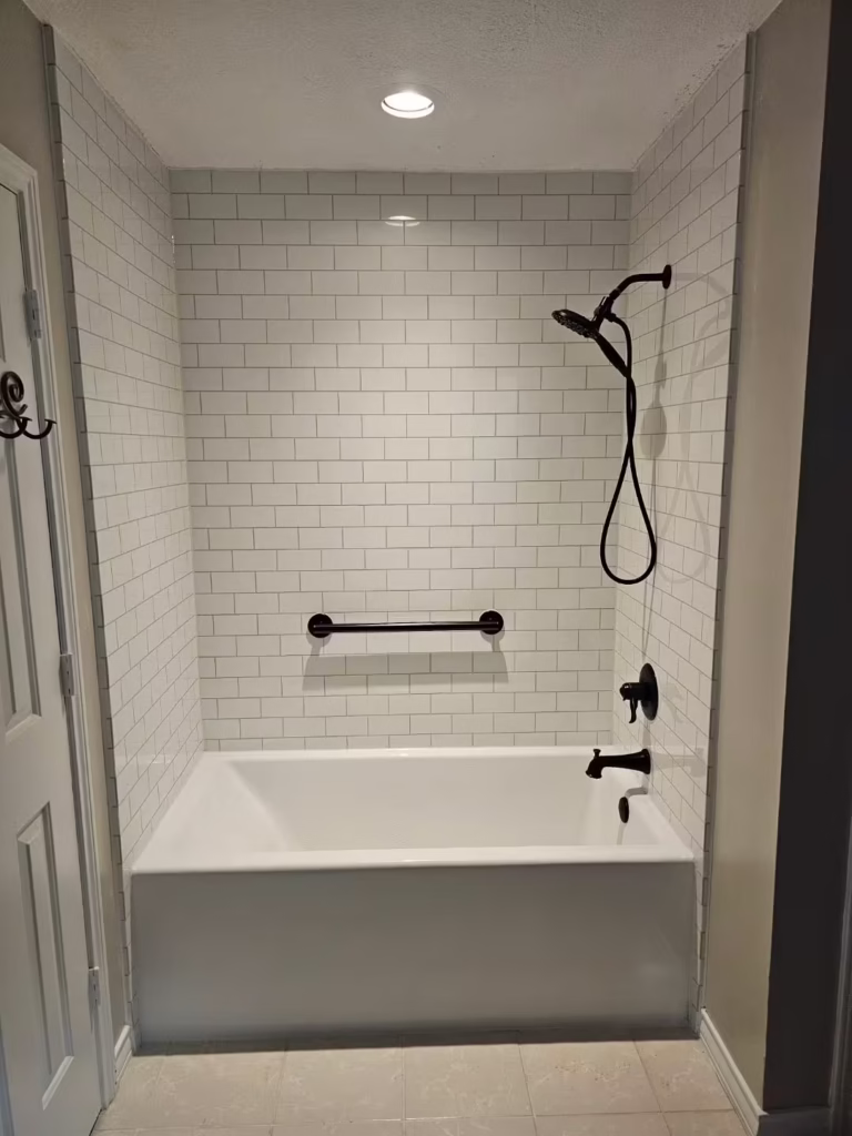 White subway tile bathtub and shower combo with black fixtures