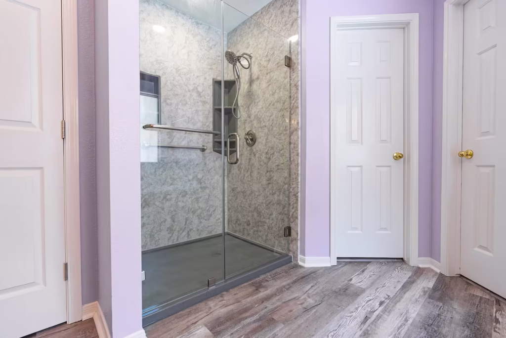 Walk-in shower with marble-pattern walls and glass door