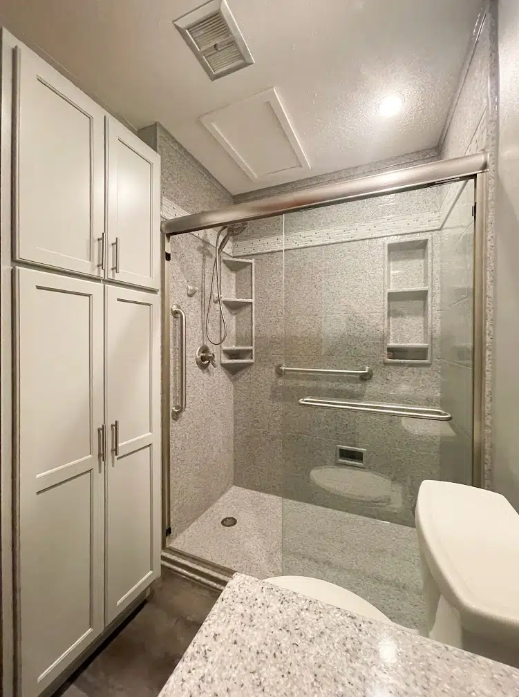 Modern bathroom with glass shower and storage cabinets.