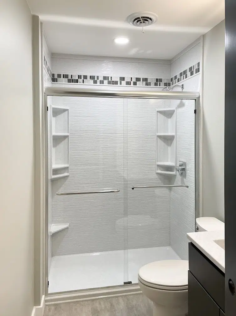 Modern bathroom with glass shower and decorative tiles.